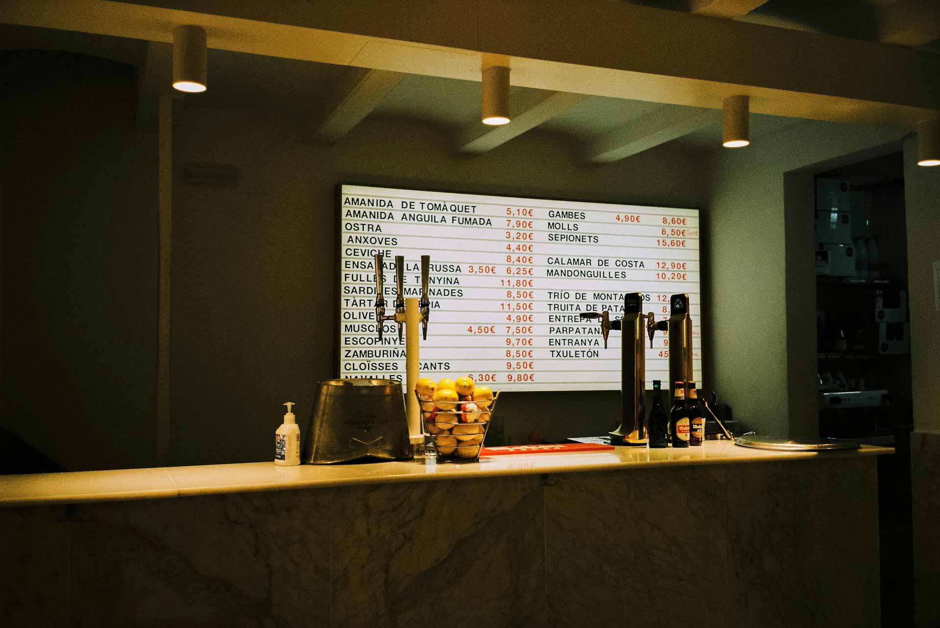 Counter of a local bar, with several options of appetizers on a white board on the wall. 