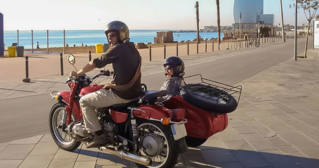 Sidecar motorcycle with a guide and a passenger stopped by the Beach in Barcelona during a private tour.