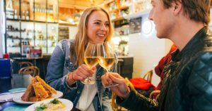 Couple toasting with spanish white wine and enjoying spanish tapas at a local restaurant during a Barcelona tapas tour by Brightside tours.