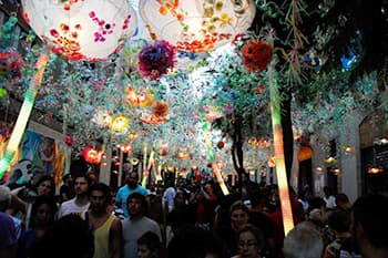People walking under decorative installation in Gracia festival