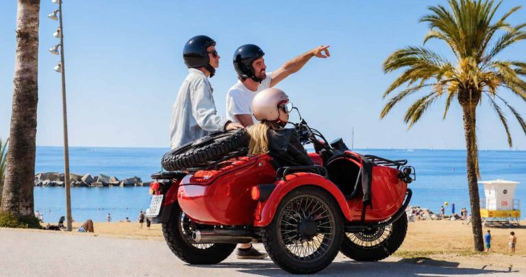 Red sidecar with tourists and guide by the beach of Barcelona.